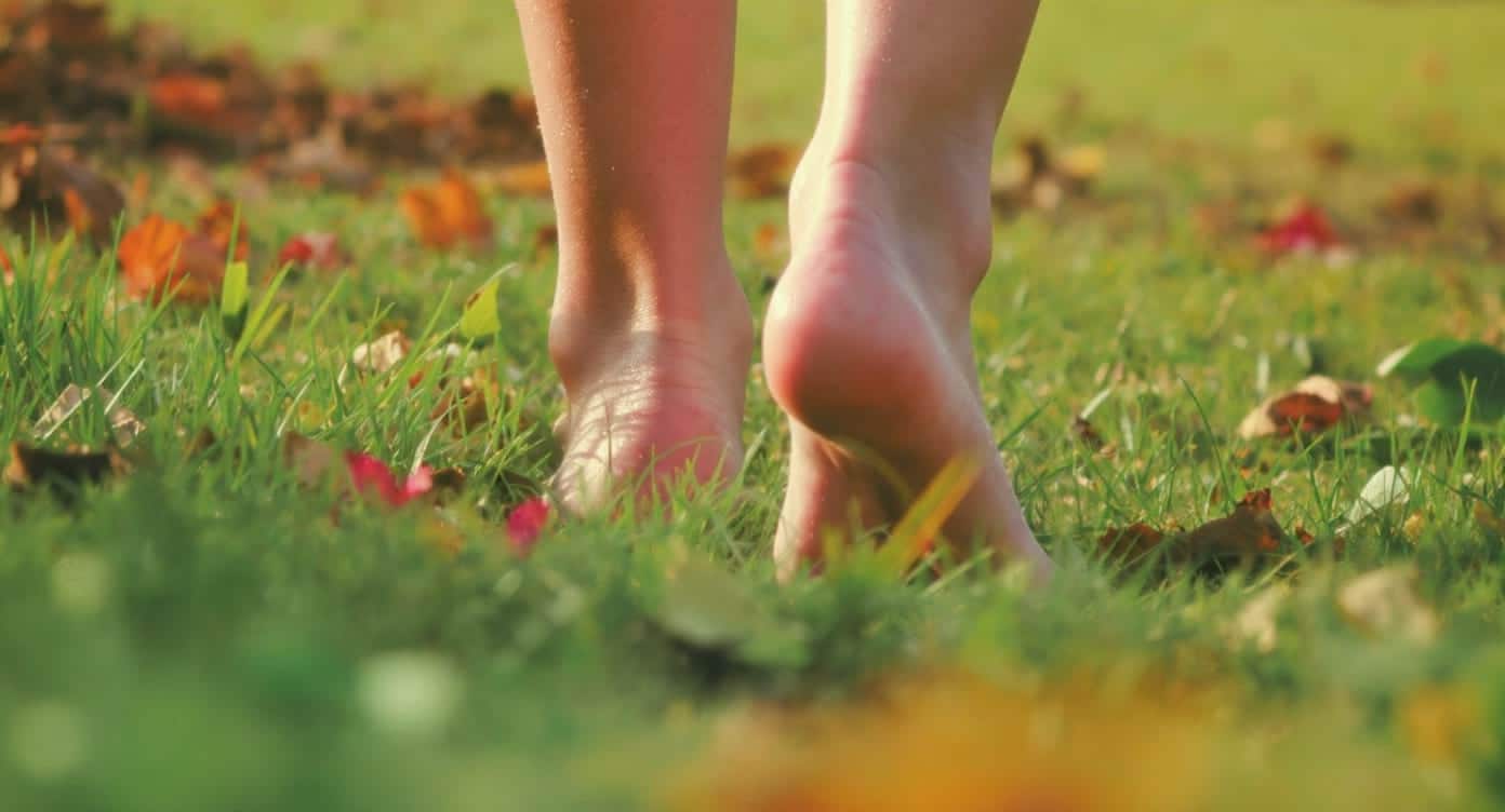 Pieds nus marchant sur l’herbe pour symboliser le confort et la santé du pied.