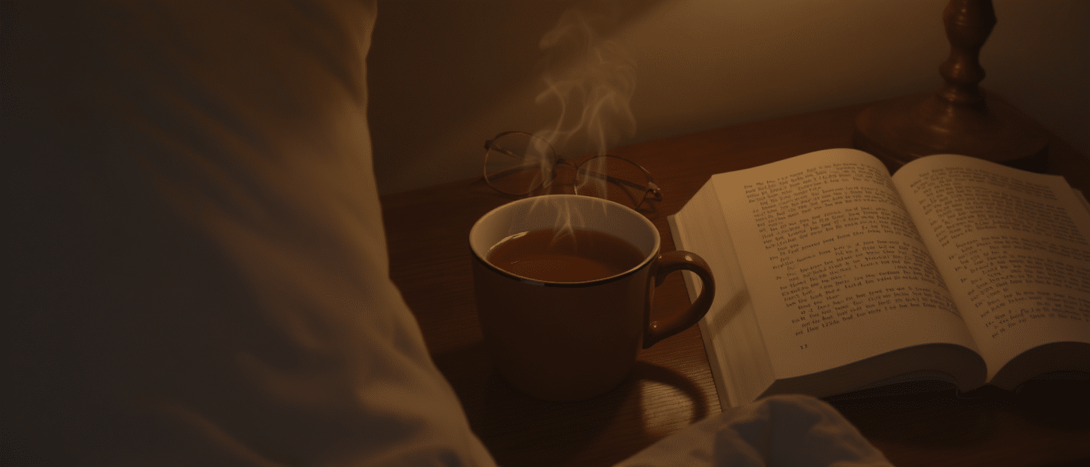 tisane-soir-rituel-apaisant Tasse de tisane fumante posée près d’un livre ouvert dans une ambiance du soir.