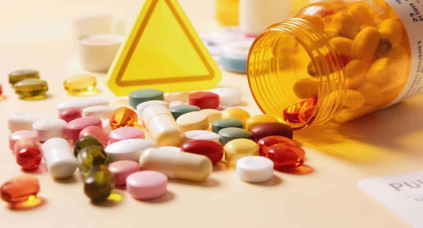 interactions-vinali-medicaments Compléments alimentaires posés à côté de médicaments sous un panneau d’avertissement