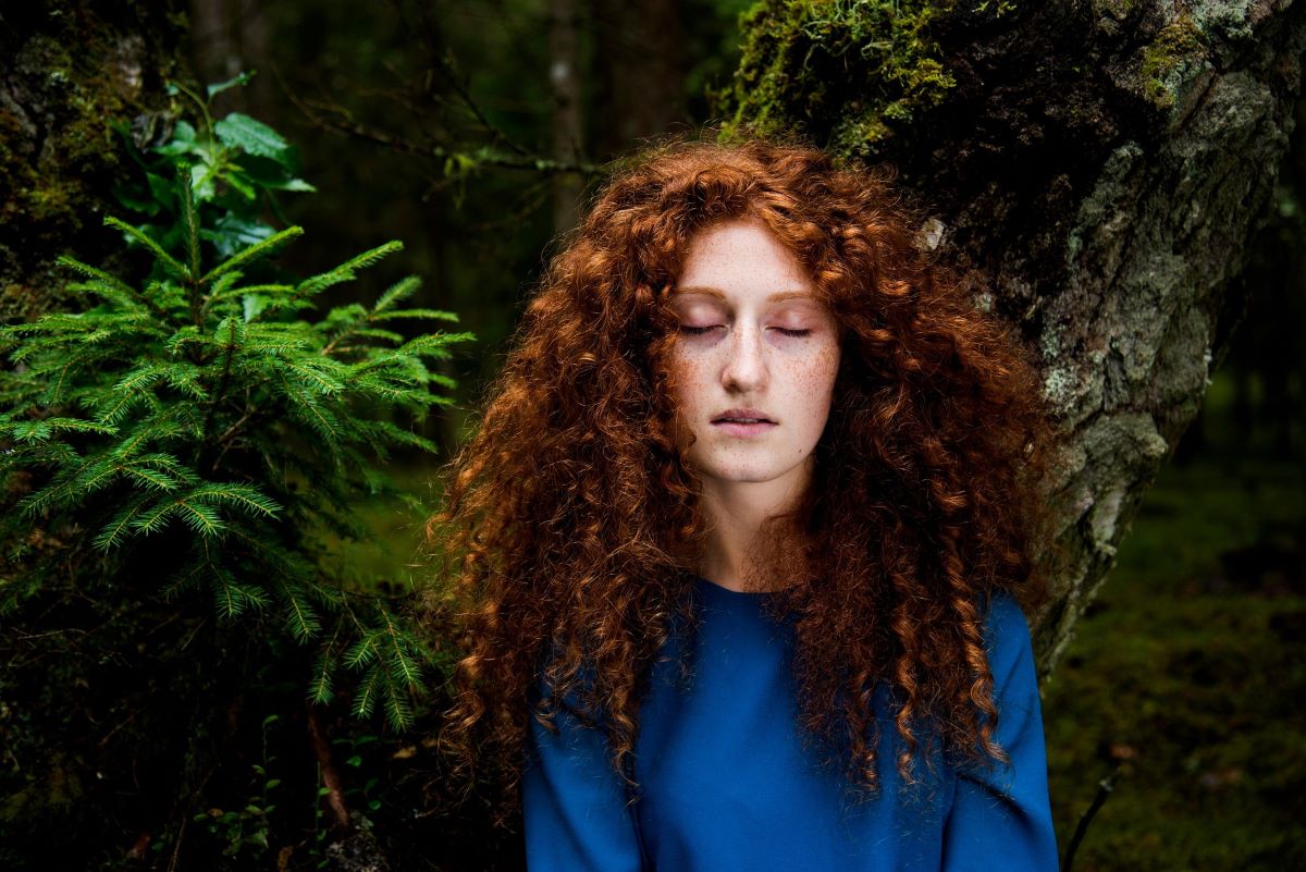 Chevelure rousse bouclée et dense, illustrant la santé capillaire naturelle